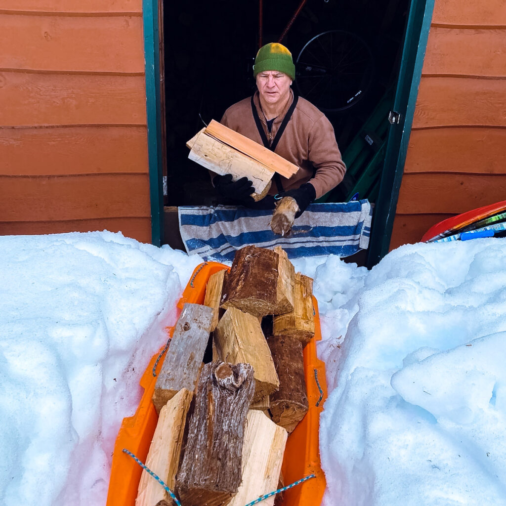 Man loading firewood into a sled.