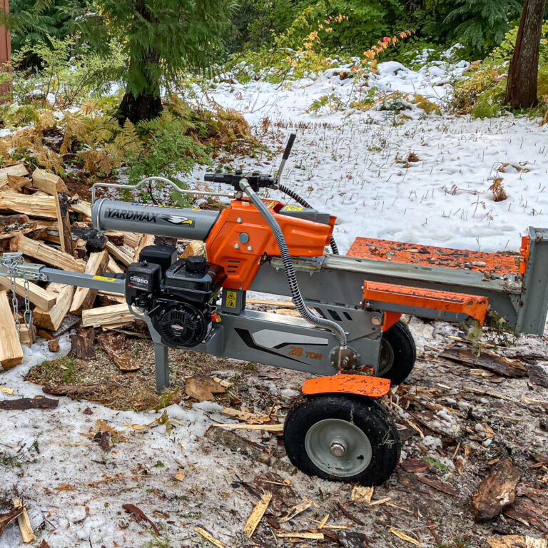 Log splitter next to a pile of wood. Snow is on the ground.